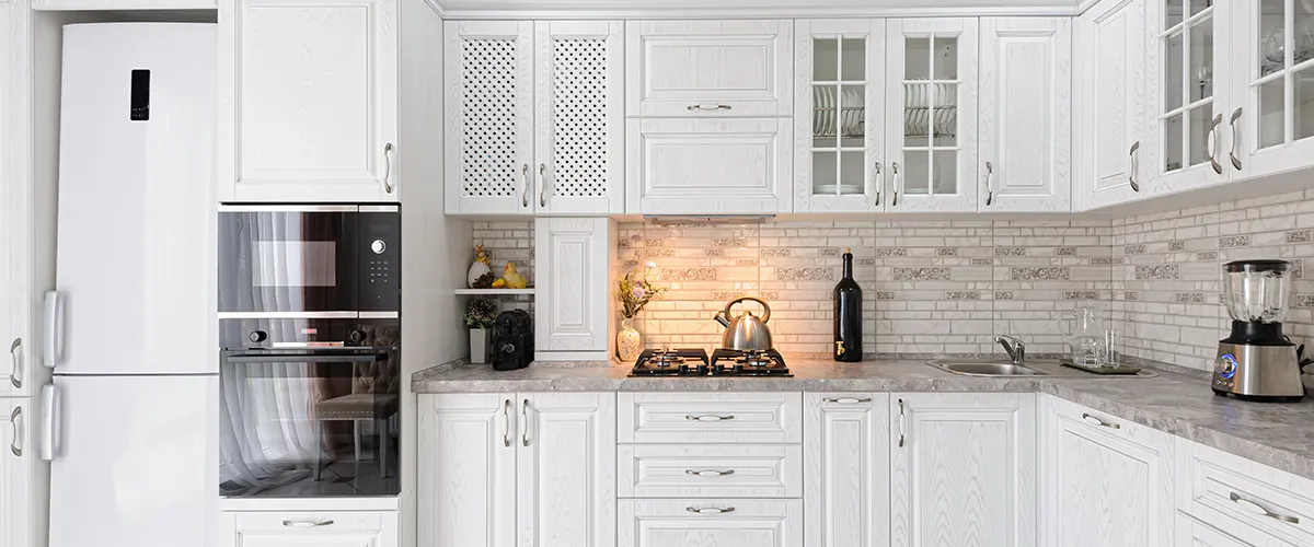 white kitchen with tile backsplash and granite countertops