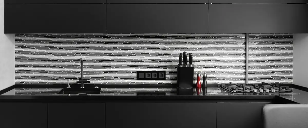 A tile backsplash in a black kitchen