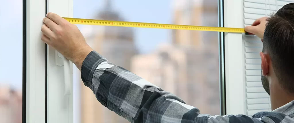 man taking measure of window for blinds installation at home