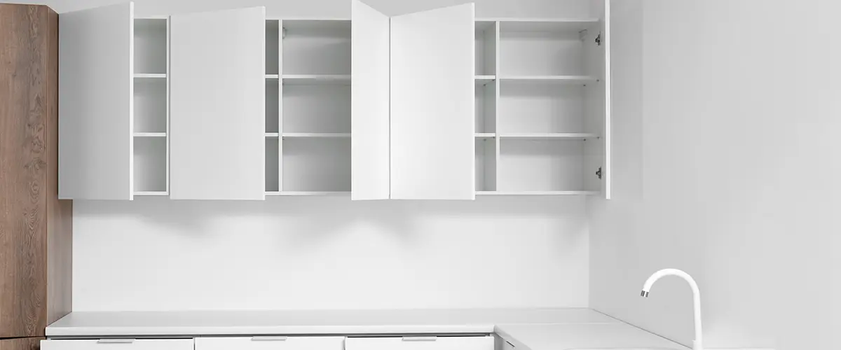 White cupboards hanging on light wall in kitchen