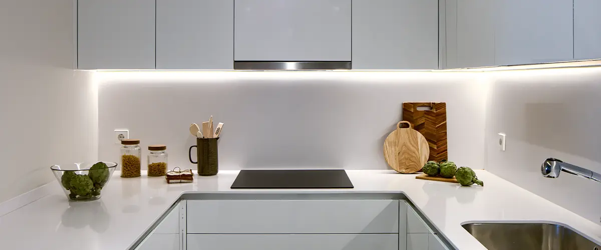 Minimalist kitchen with sleek white cabinetry, integrated lighting, and modern appliances, offering a clean and contemporary design.