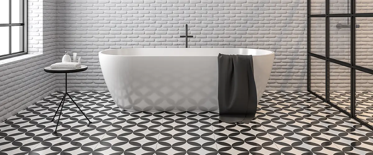 Modern bathroom with white brick walls, geometric patterned black and white floor tiles, and a freestanding bathtub