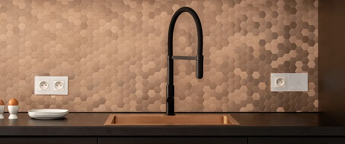 Modern kitchen with matte black cabinets, rose gold handles, a black faucet, and a copper hexagonal tile backsplash