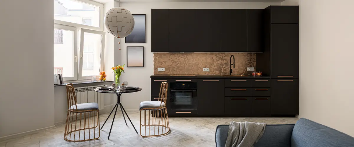 Sleek kitchen design with black cabinetry and copper accents, featuring a hexagonal tile backsplash, modern dining set, and bright window.