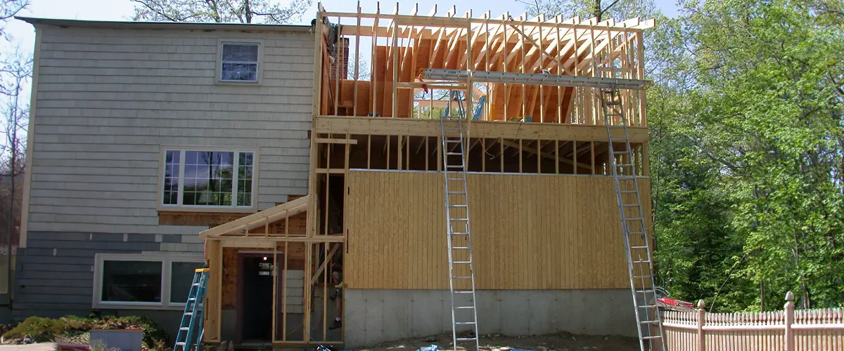 House addition in West Covina, under construction with wooden framing and ladders, showcasing a major home renovation project.