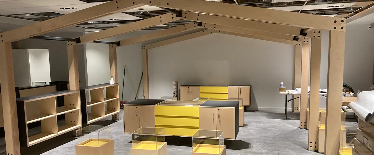 Modern commercial space under remodeling, in West Covina, with wooden shelving units, yellow accents, and an open ceiling.