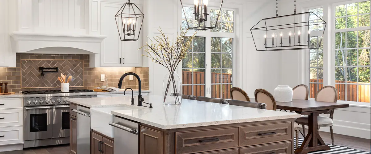 Modern kitchen with large island, white cabinetry, farmhouse sink, pendant lights, and rustic dining area - elegant open concept design.