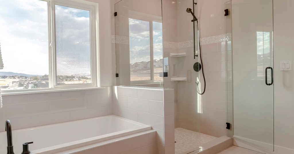 Bright bathroom with a glass shower enclosure and a large window view