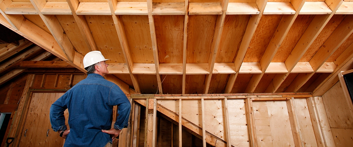 Inspector checking out attic and support beams of home addition project