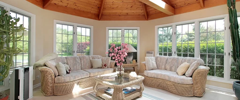 Bright sunroom with vaulted wood ceiling, large windows, and cozy wicker furniture, ideal for natural light and relaxation.
