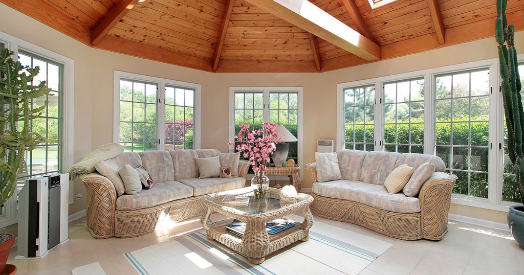 Bright sunroom with vaulted wood ceiling, large windows, and cozy wicker furniture, ideal for natural light and relaxation.